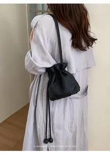 Back view detail of a black pebbled leather drawstring bucket bag on a fashion model.