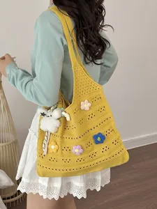 Leuchtend gelbe handgewebte Häkeltasche mit bunten Blumen und flauschigem Anhänger-Detail