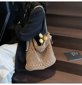 Gros plan d'un sac cabas élégant en paille tressée avec motifs floraux sur l'escalier.