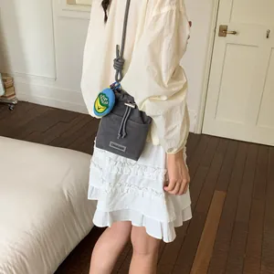 Casual grey mesh bucket bag featuring a trendy rope strap and charm, shown on a female model