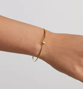 Gros plan d'un bracelet jonc délicat en argent doré orné d'une seule pierre scintillante.