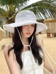 Young woman wearing a floral lace bucket hat with a wide brim on a tropical beach