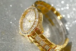 Detailed close-up of a luxury golden women's watch encrusted with sparkling rhinestones