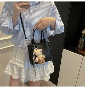 Lifestyle-Ansicht einer minimalistischen schwarzen Beuteltasche aus Leder mit Bärenanhänger