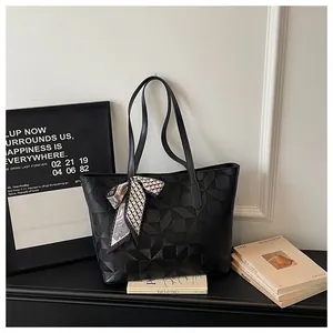Detailed view of the geometric embossed pattern and silk scarf on the black tote bag