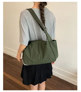 Large capacity olive green nylon tote bag worn crossbody as a lifestyle detail shot.