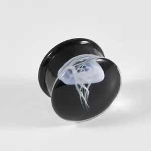 Nahaufnahme eines schwarzen Glas-Ohrstöpsels mit durchscheinendem Quallen-Design.