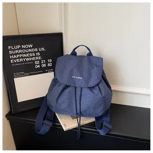 Close-up of a small blue checkered backpack with drawstring and flap closure