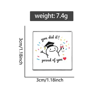 Close-up of square graduation metal badge showing 3cm dimensions and 7.4g weight