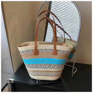 Detailansicht einer gewebten Strohtasche mit blauen Streifen und braunen Ledergriffen