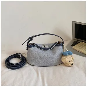 Detail shot of denim bucket bag with plush charm and leather straps