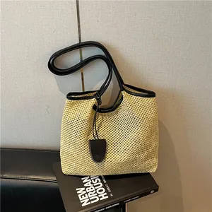 Vista dettagliata di una borsa tote in paglia intrecciata con finiture in pelle nera