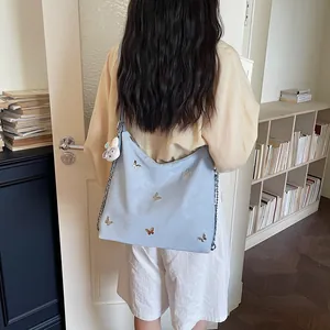 Detail view of a light blue commuter bag with butterfly accents and bunny charm