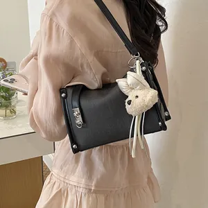 Chic black pillow bag with white plush charm, casual fashion shoulder strap detail.