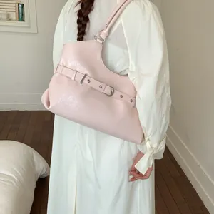 Fashionable pink underarm tote bag featuring a chic buckle strap detail worn by a model