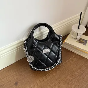 Detailed macro view of black quilted bucket bag featuring silver chain and charm