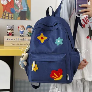 Cute dark blue backpack with colorful embroidered flower patches and a plush bear keychain