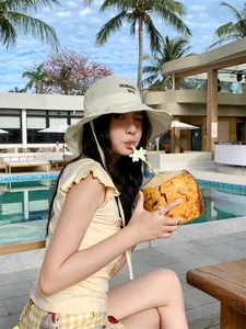Elegante cappello alla pescatora a quadretti beige con ricamo nero indossato da modella