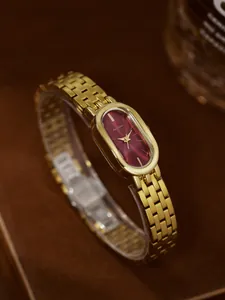 Nahaufnahme einer goldenen Vintage-Uhr mit ovalem burgunderrotem Zifferblatt