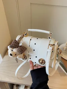 Elegant vintage white polka dot handbag featuring a cute bear charm and gold hardware accents