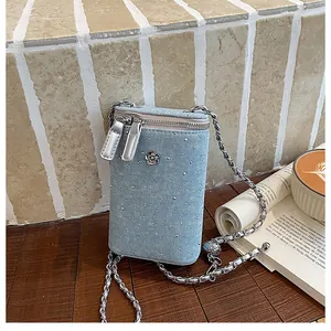 Detailed view of light blue denim crossbody phone bag with rhinestones and silver chain.