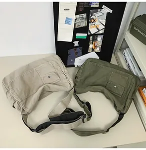 Detailed view of beige and olive green large canvas messenger bags on a stylish table
