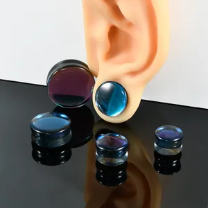 Detailed macro view of black AB glass ear plugs with iridescent reflections on black surface