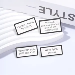 Close-up of 4 square enamel brooches with witty English phrases on white wave stand.