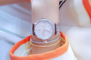 Primer plano de reloj plateado para mujer con esfera de pedrería y pulseras a juego.