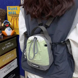 Detaillierte Nahaufnahme der leichten grün-grauen Umhängetasche, getragen als Minirucksack.