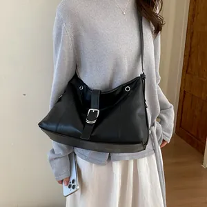 Stylish black leather crossbody tote bag shown on a model with a casual grey sweater