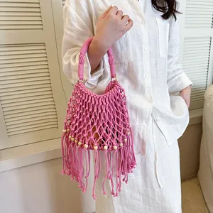 Detailed view of pink handmade macramé bucket bag with bohemian fringe and wooden beads