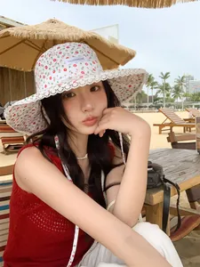 Beautiful Asian model wearing a floral lace bucket hat at a sunny summer beach resort setting