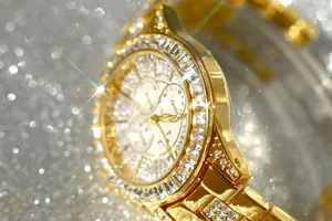 Close-up detail of a luxury gold-toned watch with full square diamond bezel decoration