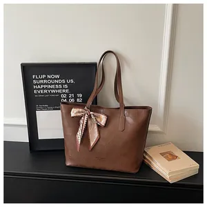 Detailed view of brown leather tote bag with geometric pattern and decorative scarf