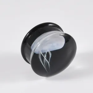 Nahaufnahme eines schwarzen Glas-Ohrplugs mit einem durchsichtigen weißen Quallenmuster