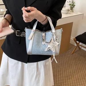 Close-up of a light blue denim bucket bag with silver trim and a sequined star charm