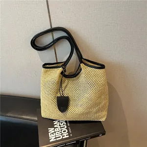 Dettaglio della trama in paglia intrecciata e bordi in pelle nera sulla borsa da mare