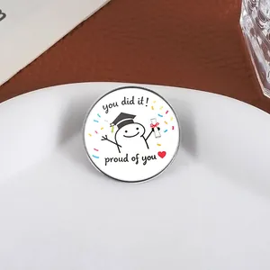 Detailed close-up of a cartoon graduation pin with 'you did it!' message on a white plate