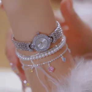 Close-up detail of luxury silver BS rhinestone watch styled with pearl bracelets