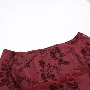 Détail du tissu en maille et du nœud en velours sur le haut bordeaux fleuri chic.