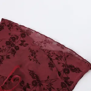 Gros plan sur le tissu en maille bordeaux avec des détails floraux sombres.