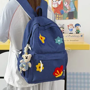 Detail of navy blue student backpack with colorful flower patches and cute bear charm