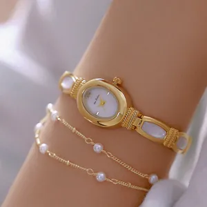 Primer plano de un reloj de pulsera dorado con elegantes incrustaciones de nácar blanco.