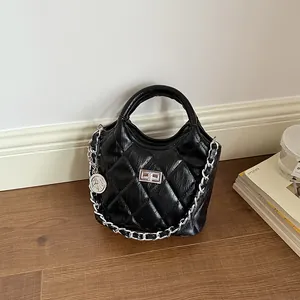 Close-up view of black quilted leather bucket bag with silver chain strap and coin charm