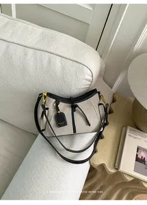 Bolso de hombro de lona casual con ribete de cuero negro en un sofá blanco