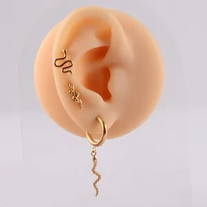Detail view of golden stainless steel snake earrings set on a silicone ear model.