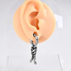 Gros plan d'une boucle d'oreille nœud en argent antique avec texture martelée sur modèle