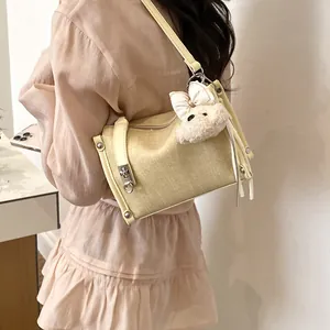 Detail of cream textured shoulder pillow bag featuring a cute plush bear charm and lock.