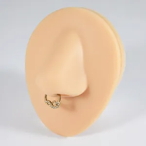 Close-up of gold plated stainless steel septum ring with white zircon on a nose model